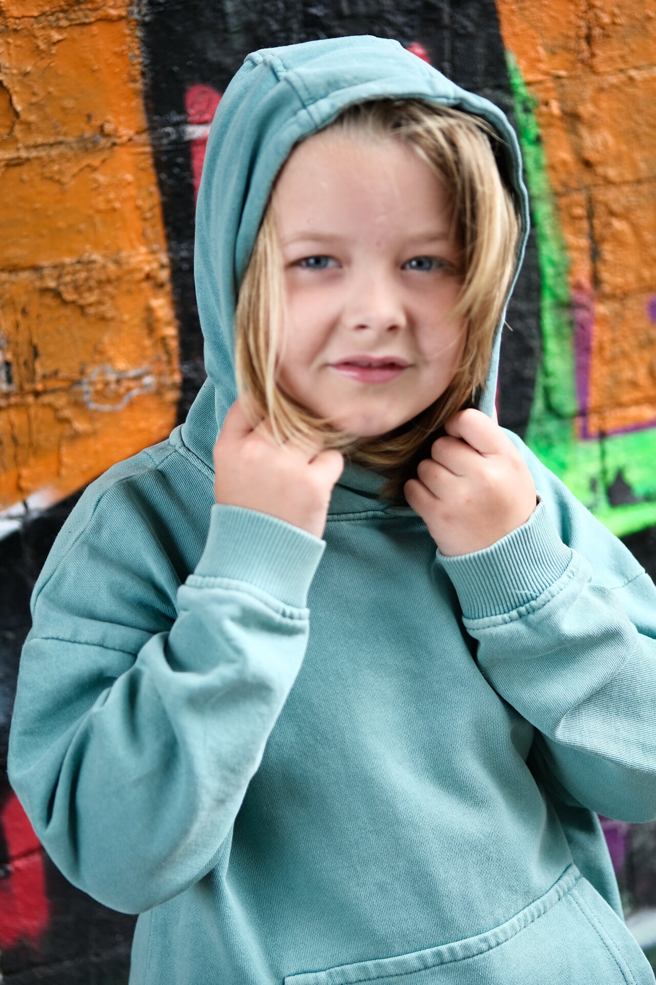 George Rouse three-quarter shot wearing mint green hoodie against colorful graffiti wall background