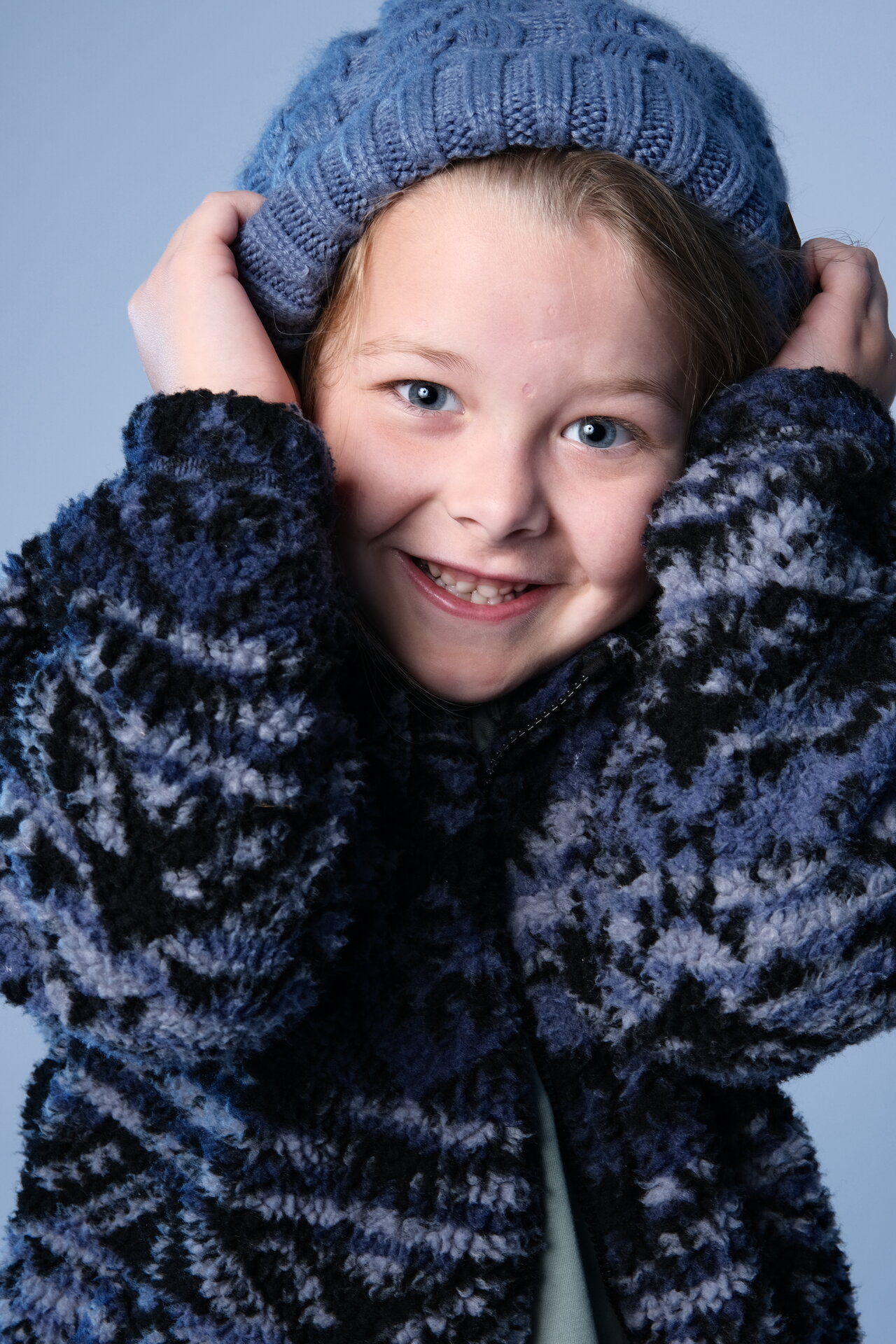 George Rouse - Professional child model with blonde hair, wearing blue knit beanie and patterned sweater, smiling warmly at camera